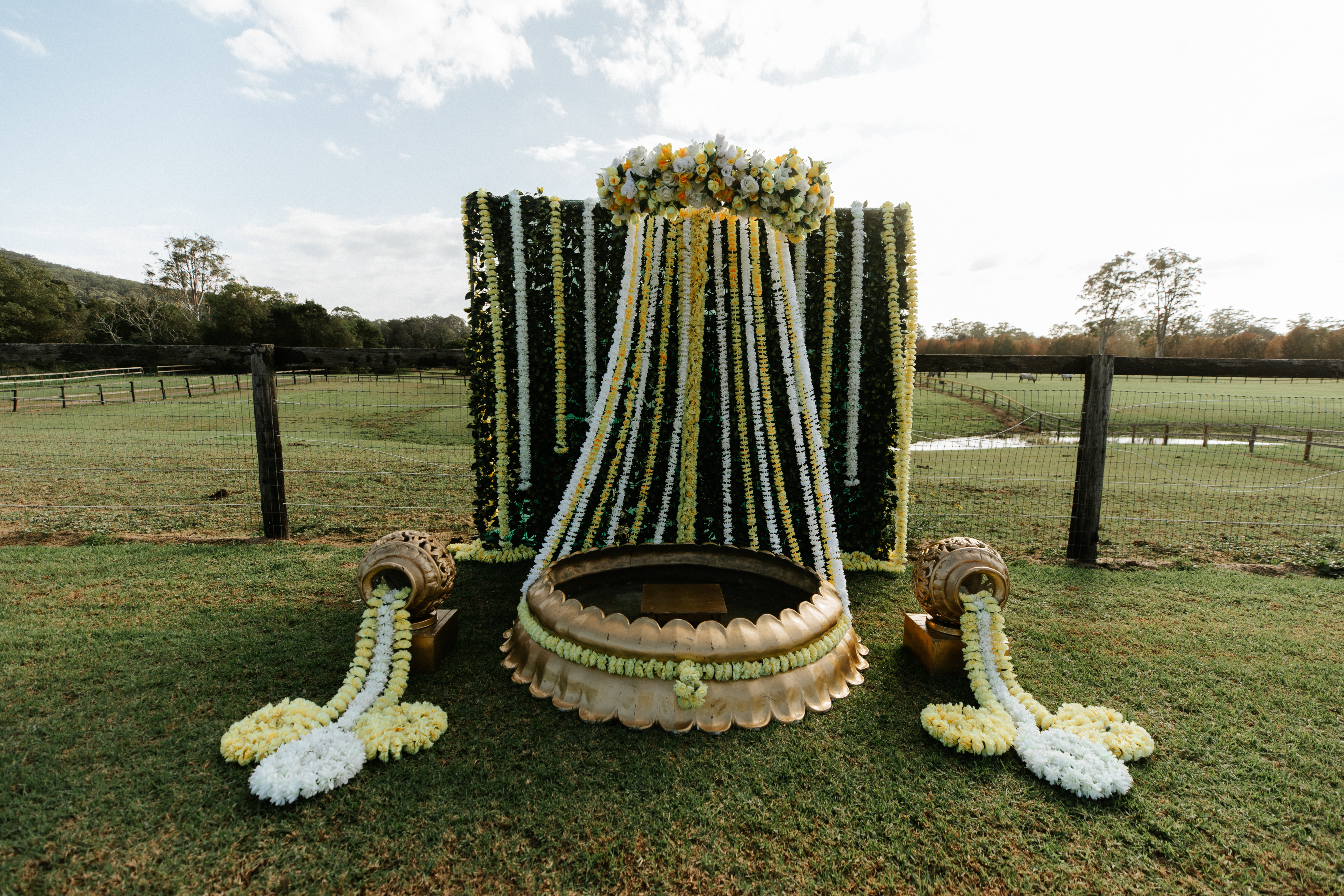 Haldi backdrop of marigold and white flower garlands with a gold seat on a private Central Coast property