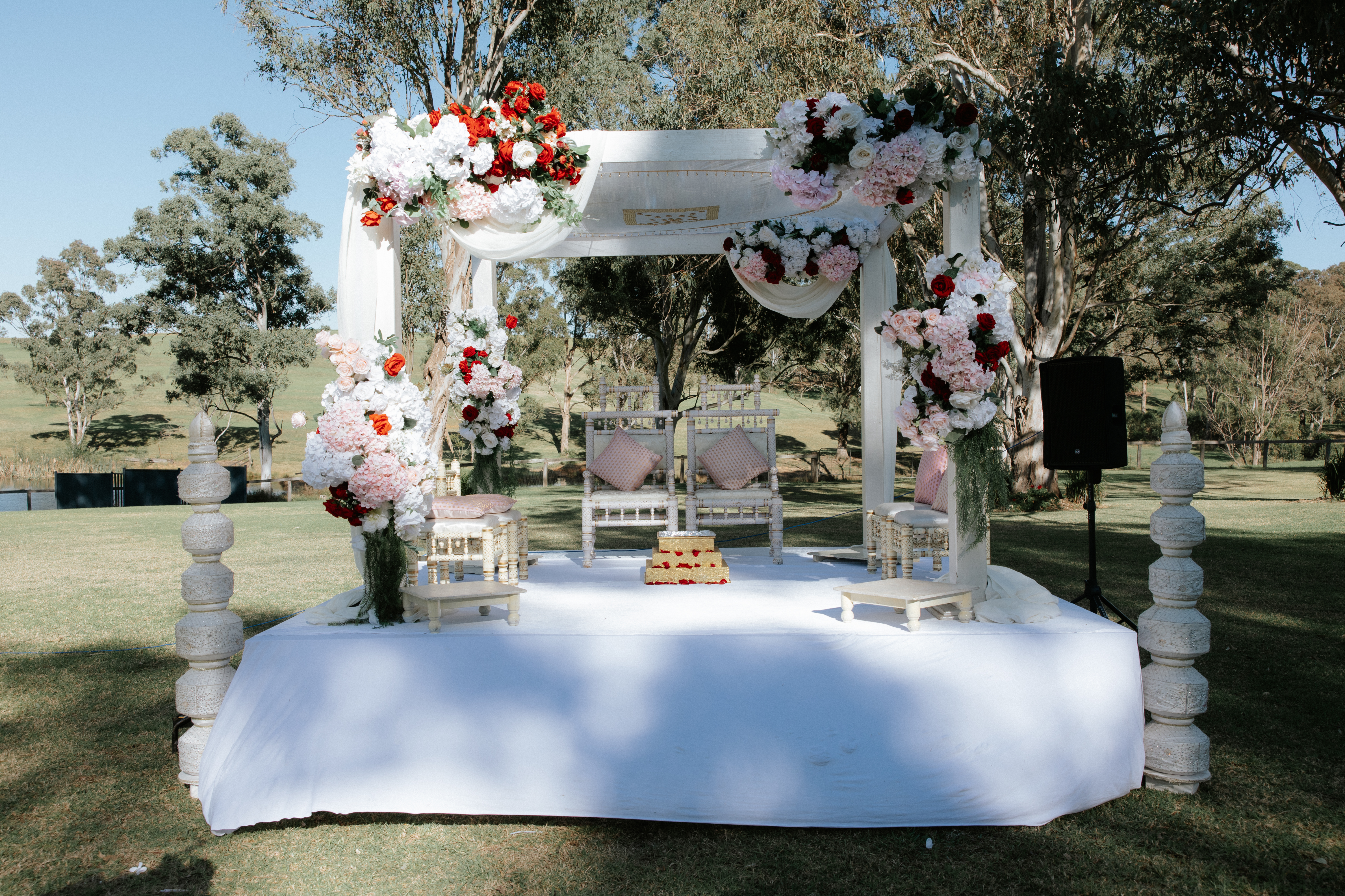 Outdoor mandap dressed in red, pink and white florals on the lawn at Ottimo House, Sydney
