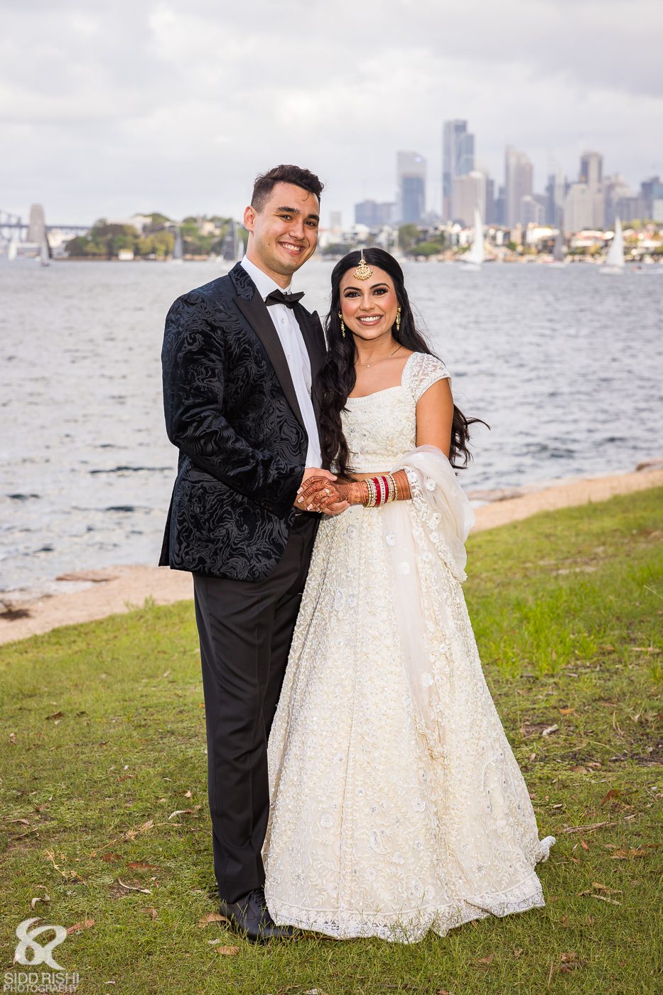 Shubhra and Morgan by the water at Deckhouse Woolwich, with the Sydney skyline behind them