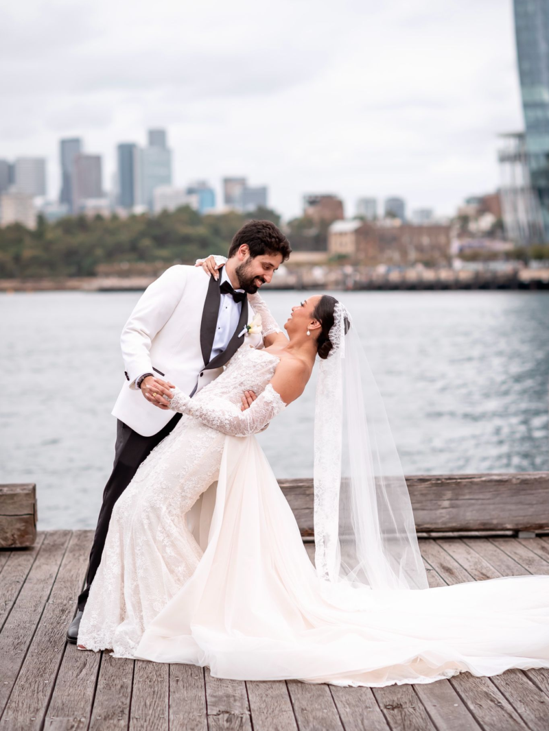 Shania and Anshul on a Sydney harbour wharf, the bride in a white gown and veil