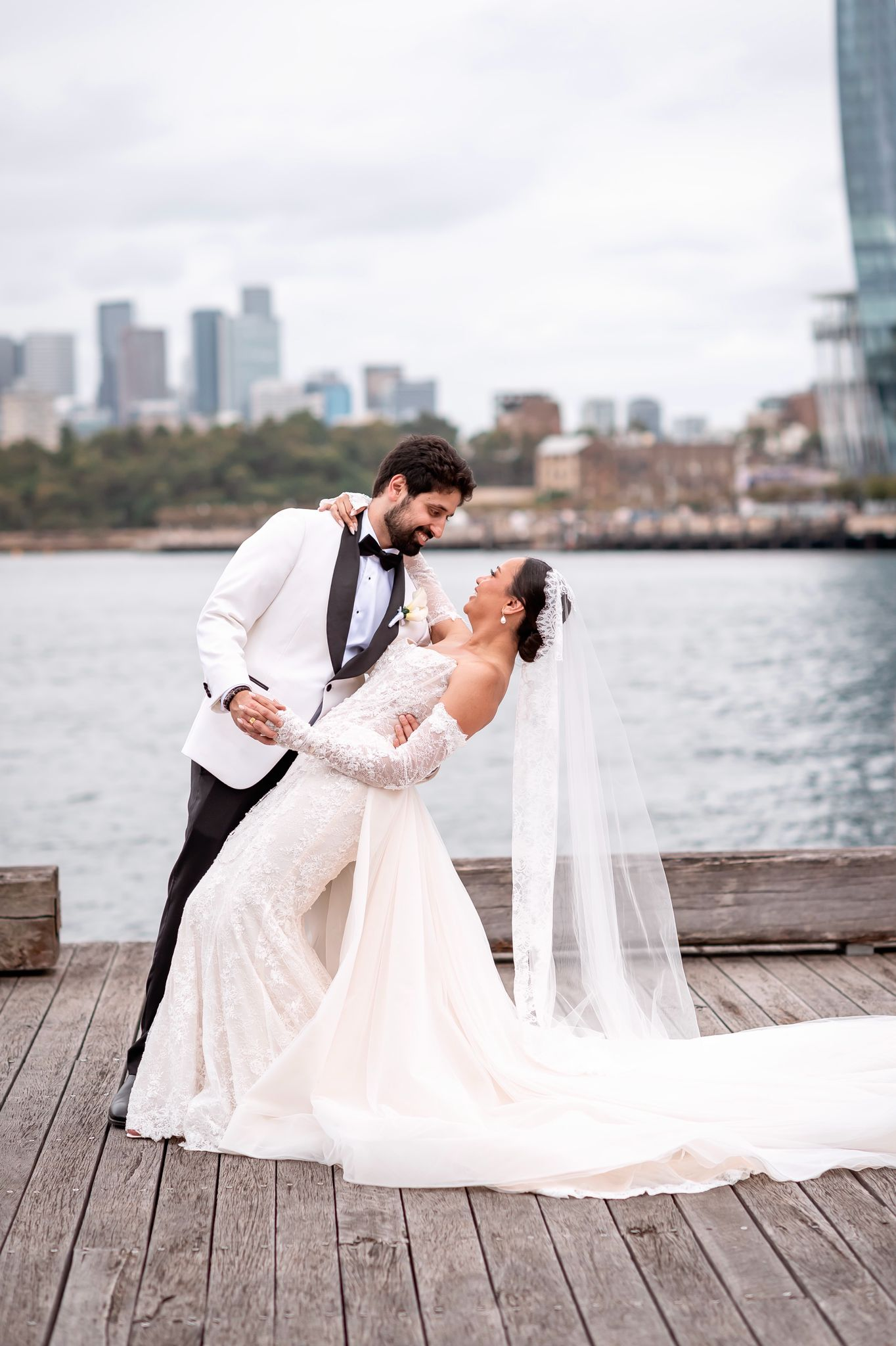 Shania and Anshul on a Sydney harbour wharf, the bride in a white gown and veil