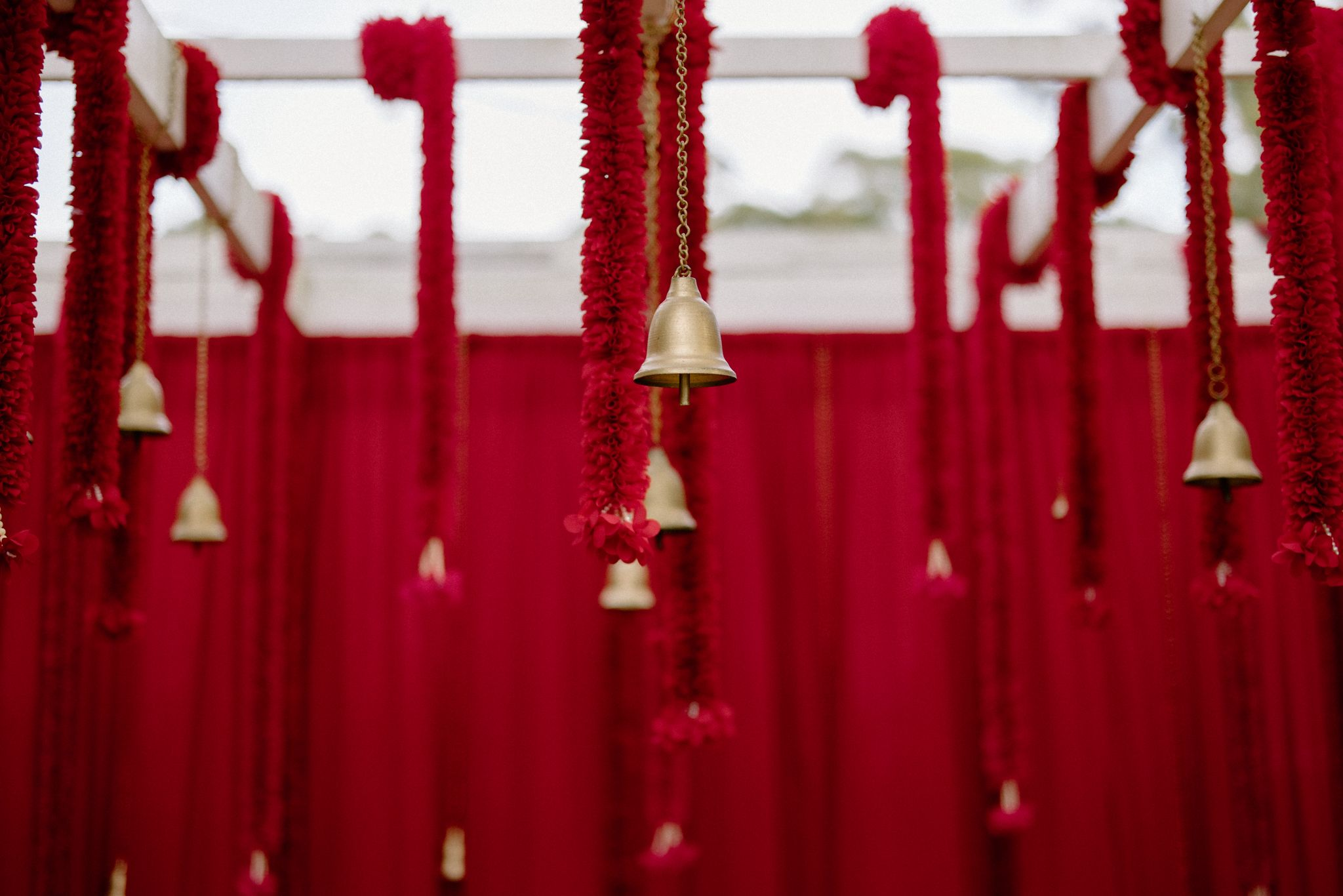 Gold bells hanging from red marigold and tassel garlands at a South Indian Hindu wedding mandap in Sydney